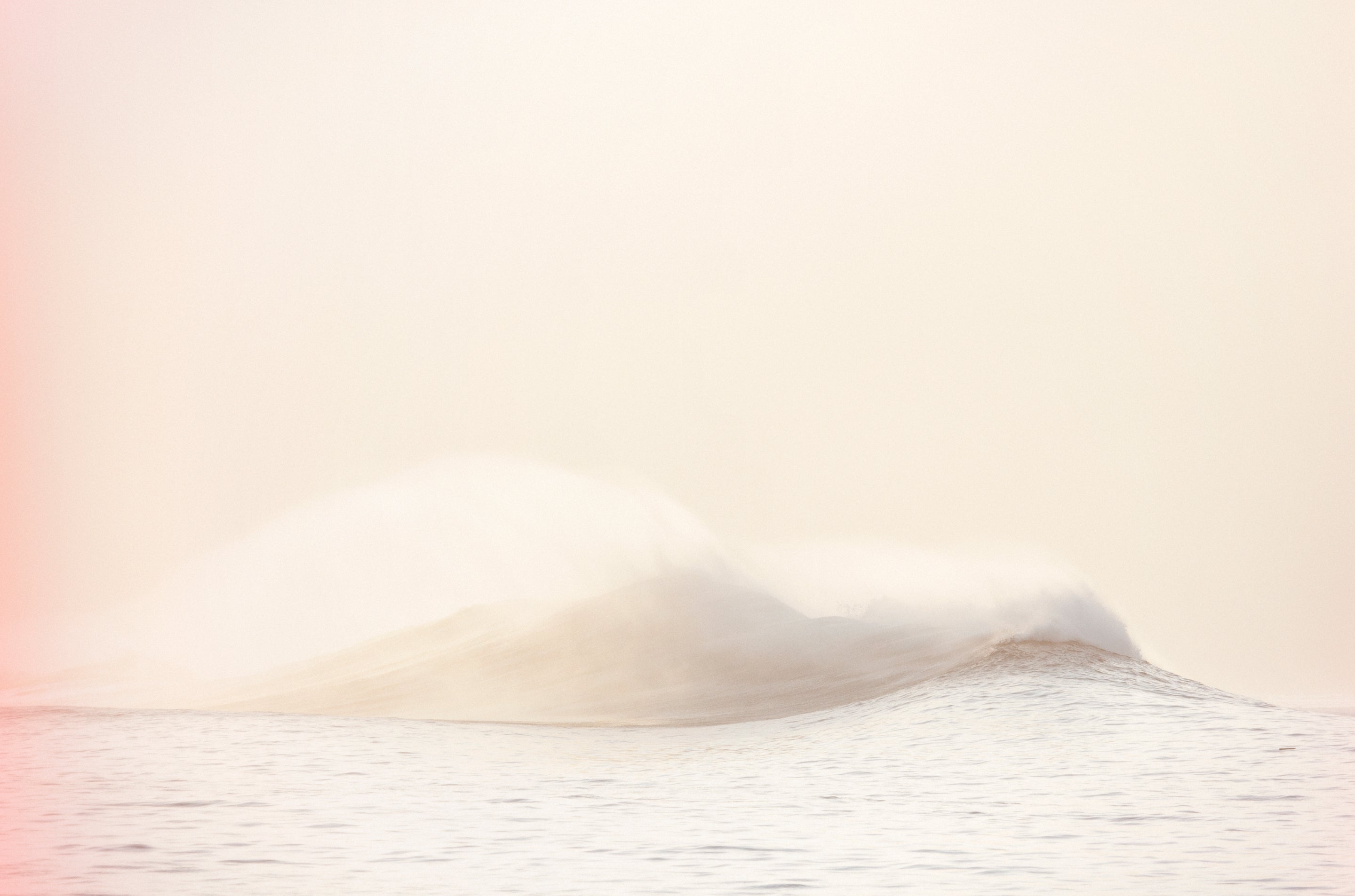 A soft, minimalist seascape with a gentle wave cresting on calm water under a pale peach and cream sky.